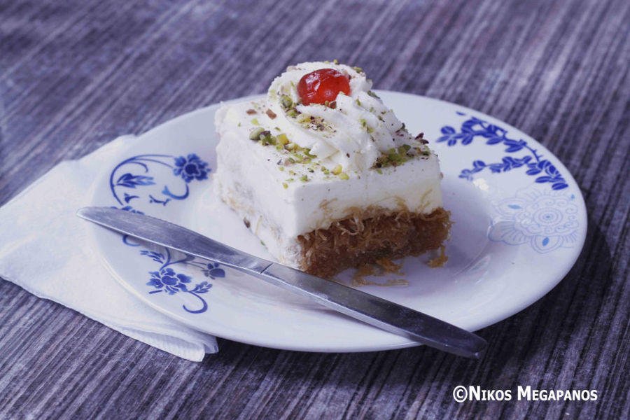 Close-up of plate with Greek ‘Ekmek kataifi’ means pan-baked sweet covered with syrup and whipped cream on top